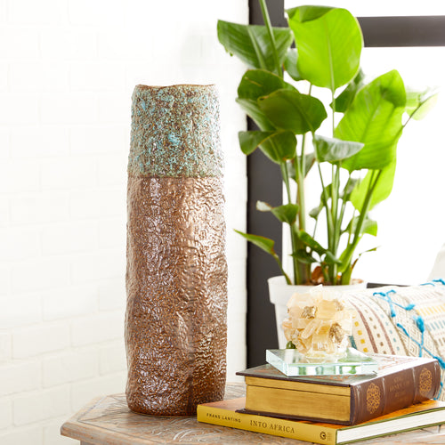 Jarrón de cerámica cilíndrico con apariencia de pátina sobre bronce.